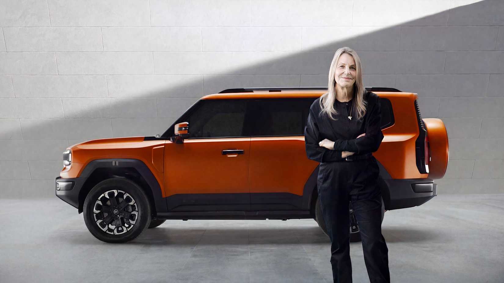 Foto lateral de um JETOUR G700 estacionado em estúdio com a designer Paula Scher, em frente