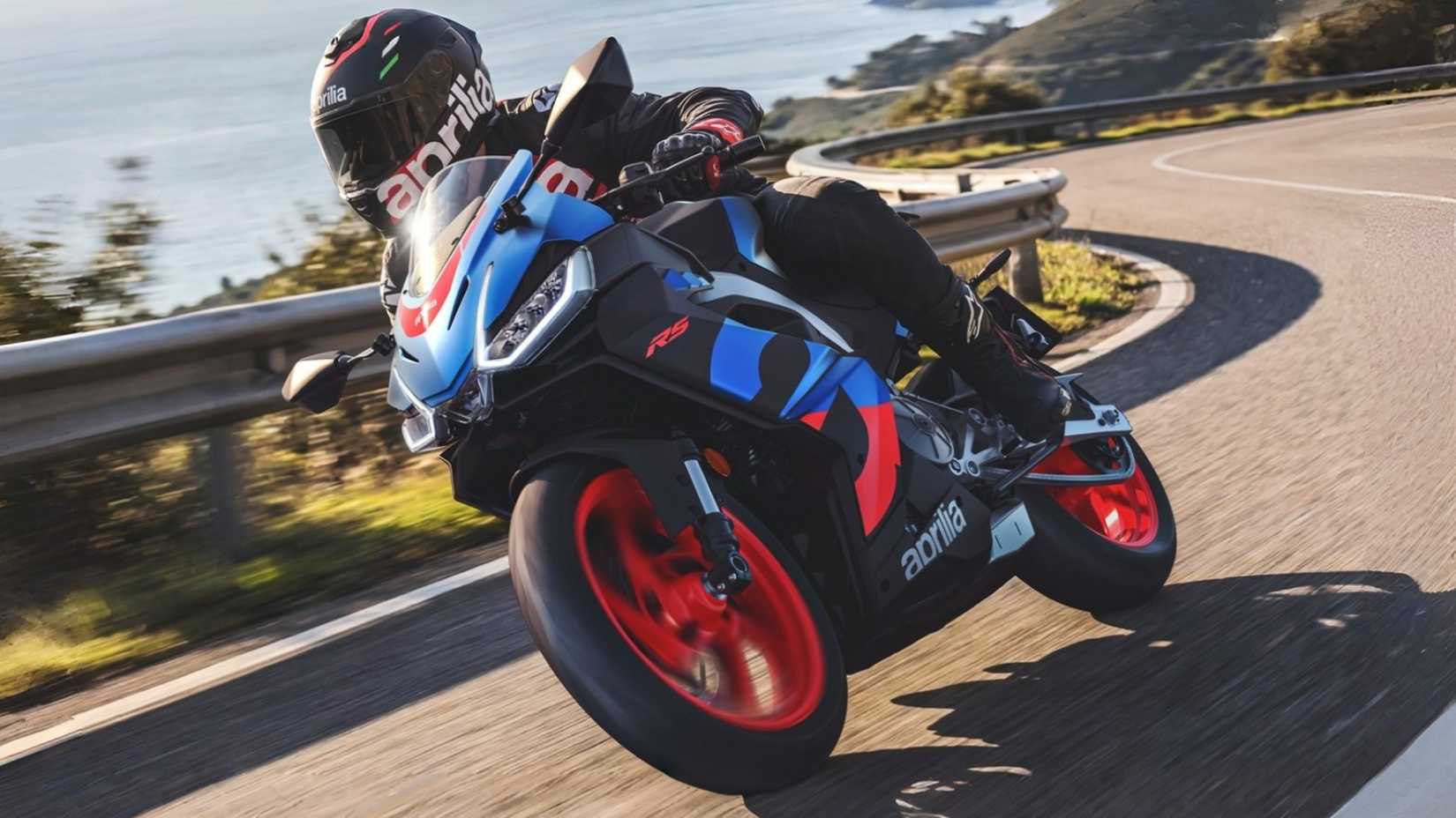 Bicicleta esportiva Aprilia RS 457 2026 fazendo curvas ao longo de uma estrada de montanha,