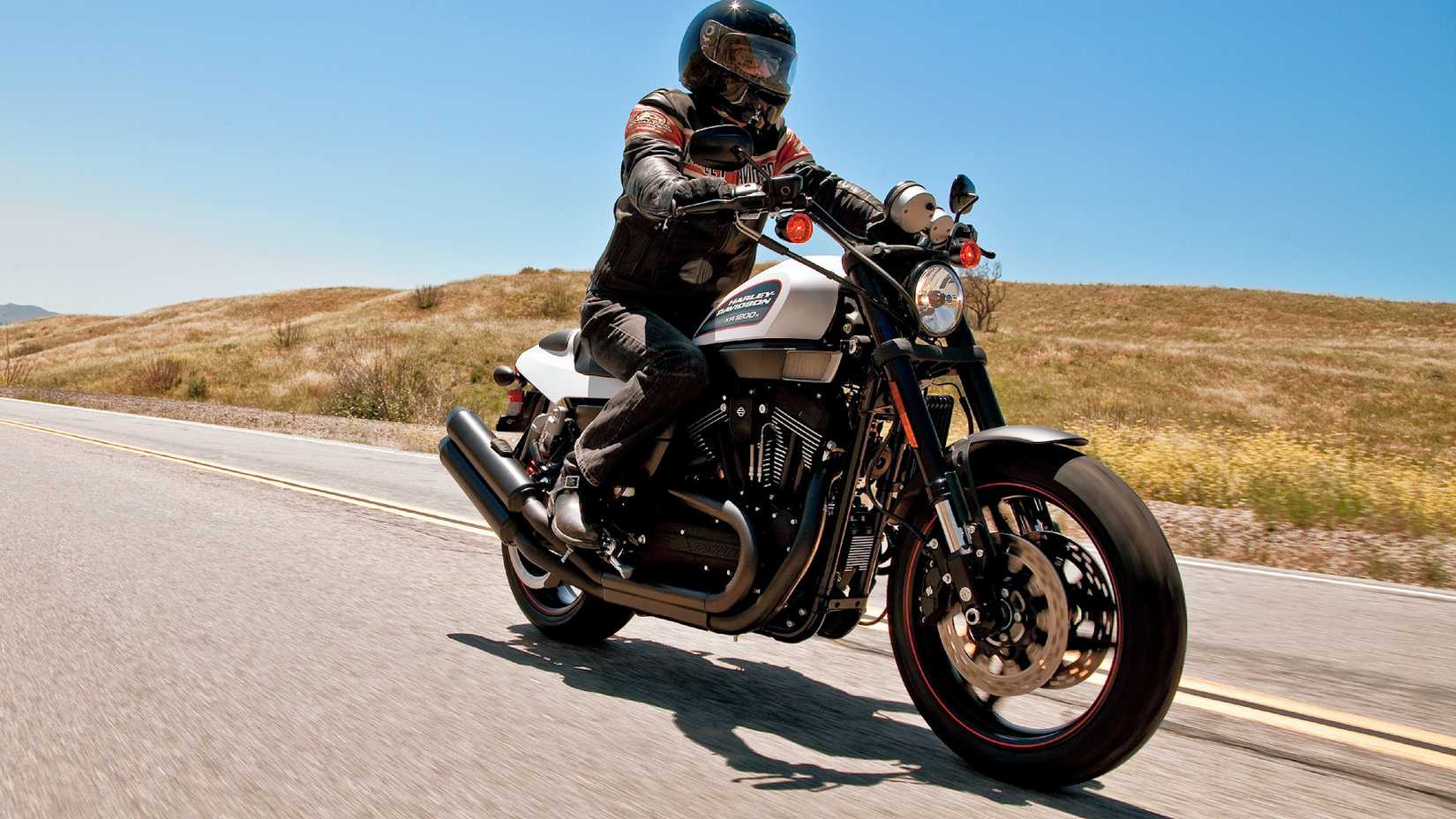 Piloto em uma Harley-Davidson XR1200X 2011 viajando em uma estrada rural