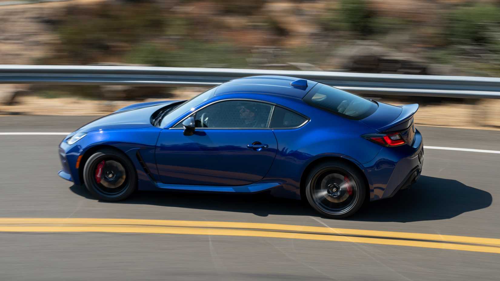 Foto lateral de um Toyota GR86 2027 azul em movimento na estrada