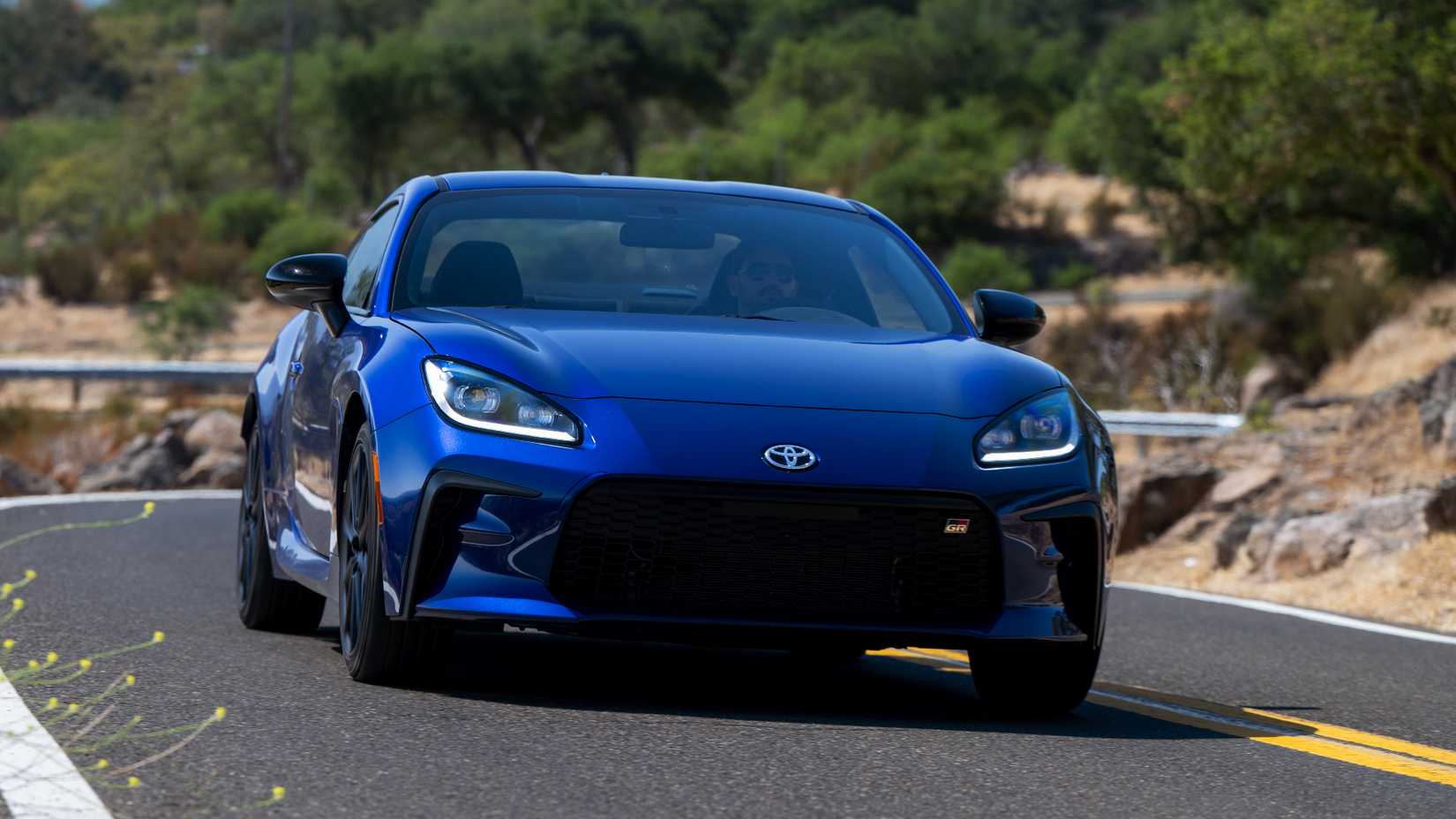 Front shot of a blue 2027 Toyota GR86 in motion