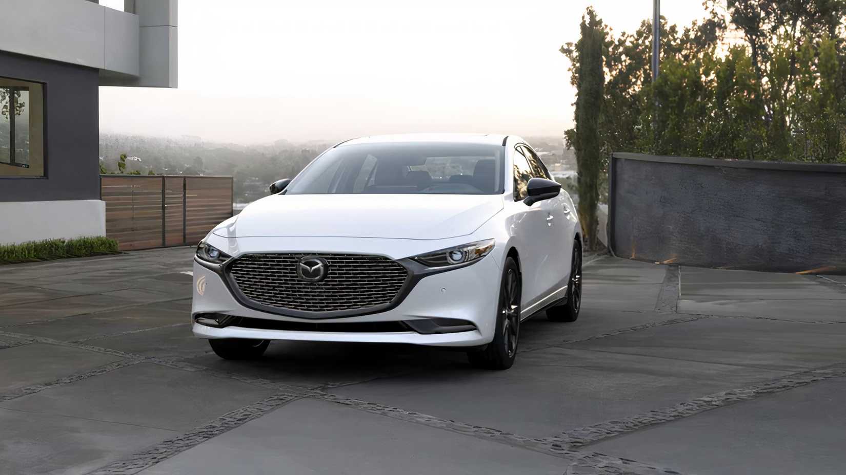 Front 3/4 shot of 2026 Mazda 3 Sedan in white parked
