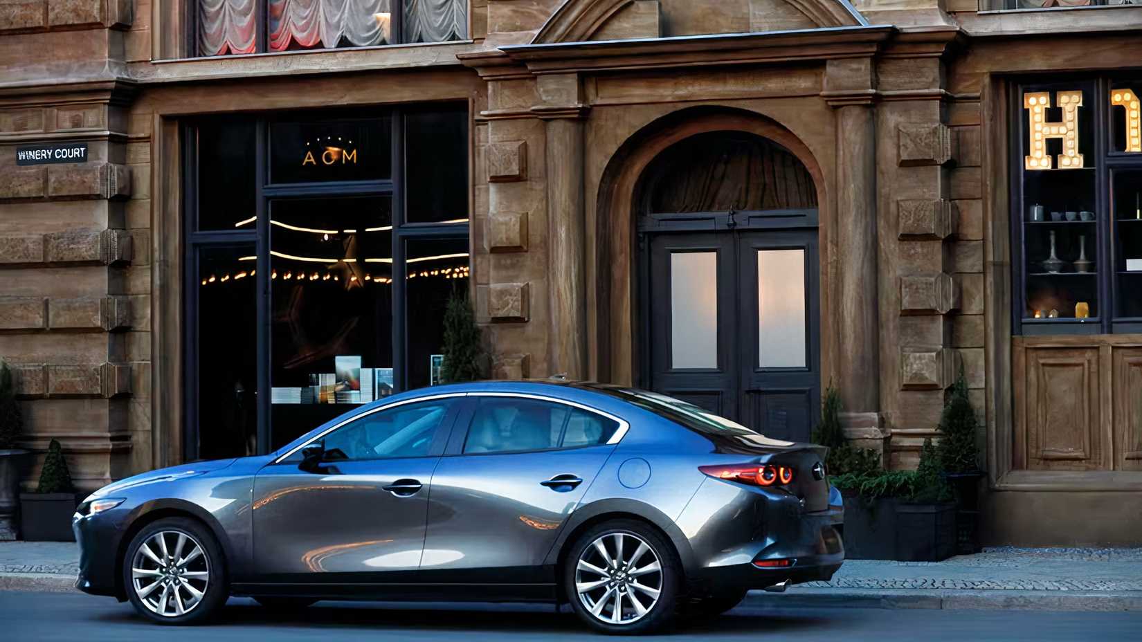 Rear 3/4 shot of 2026 Mazda 3 Sedan parked on city street