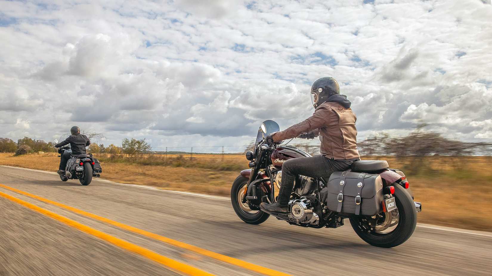 Pilotos em modelos 2022 Indian Super Chief Limited viajando em uma estrada rural