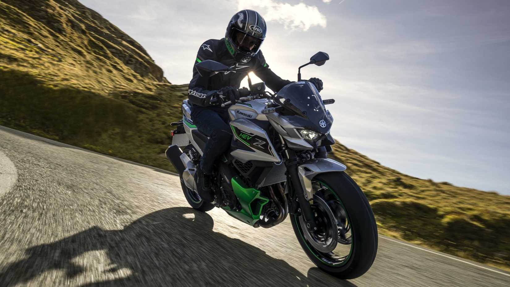 Kawasaki Z7 Hybrid se inclinando vigorosamente em uma estrada sinuosa na montanha, vista frontal do terceiro quarto