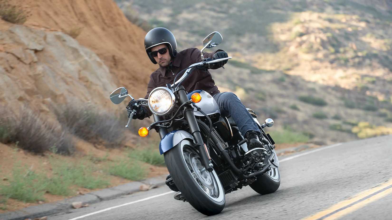 Action shot of a 2026 Kawasaki Vulcan 900 Classic riding on a mountain road