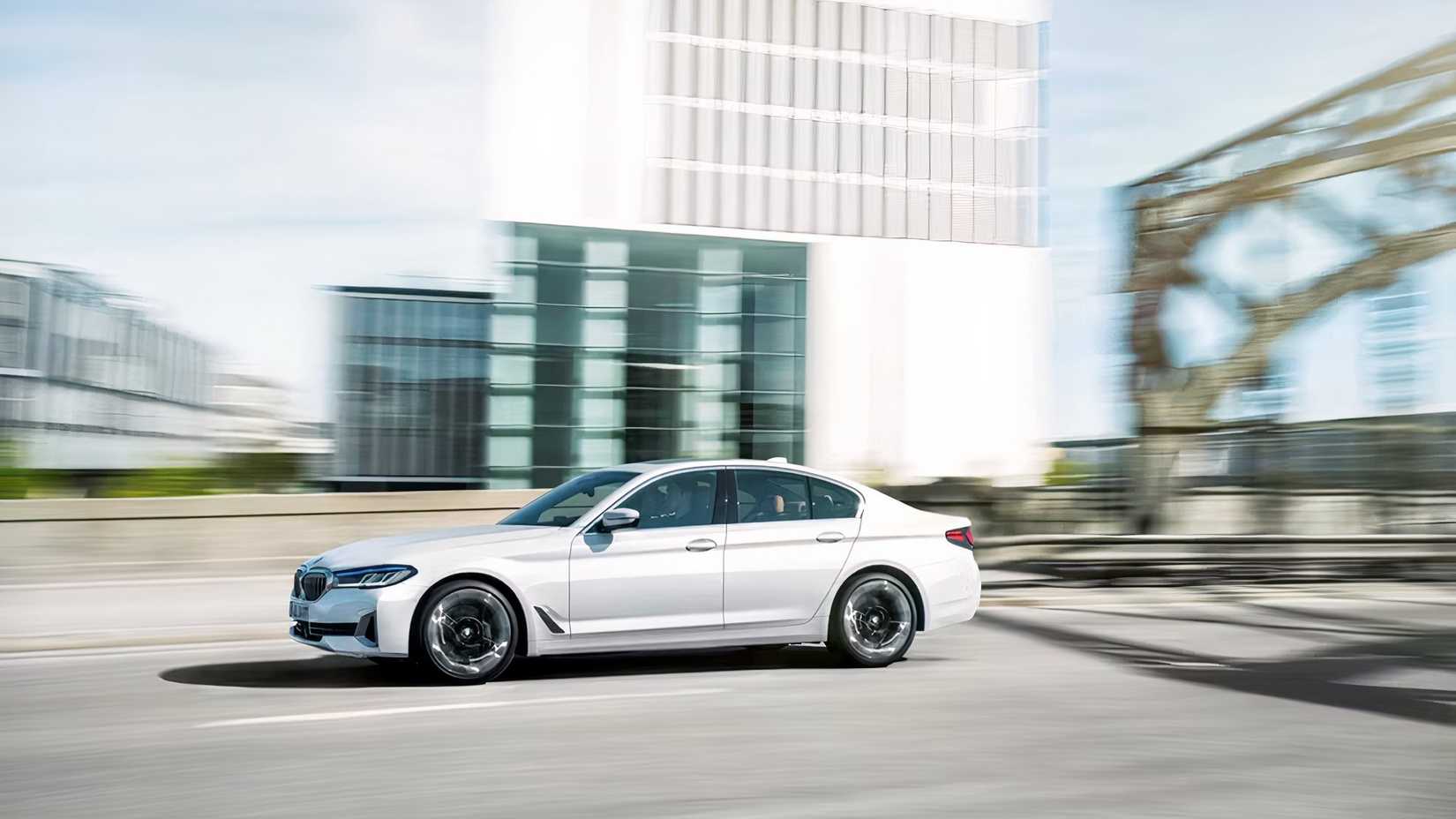 Profile action shot of 2021 BMW 5 Series sedan driving on road