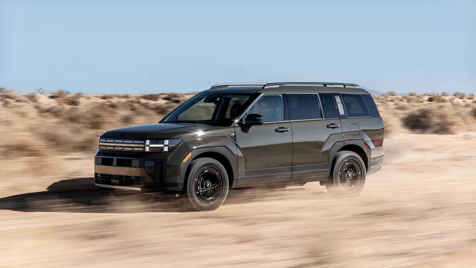 Front 3/4 action shot of 2026 Hyundai Santa Fe driving in desert