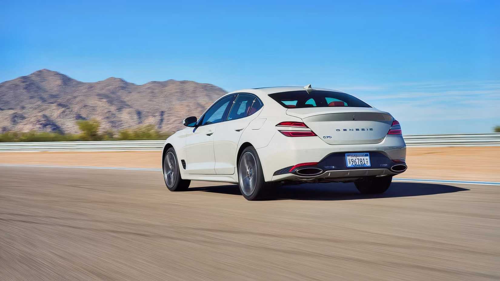 Rear 3/4 action shot of 2026 Genesis G70 driving on road