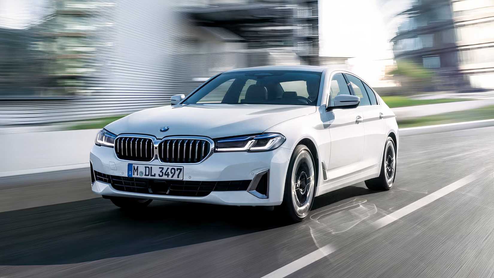 Front 3/4 action shot of 2021 BMW 5 Series sedan driving on road