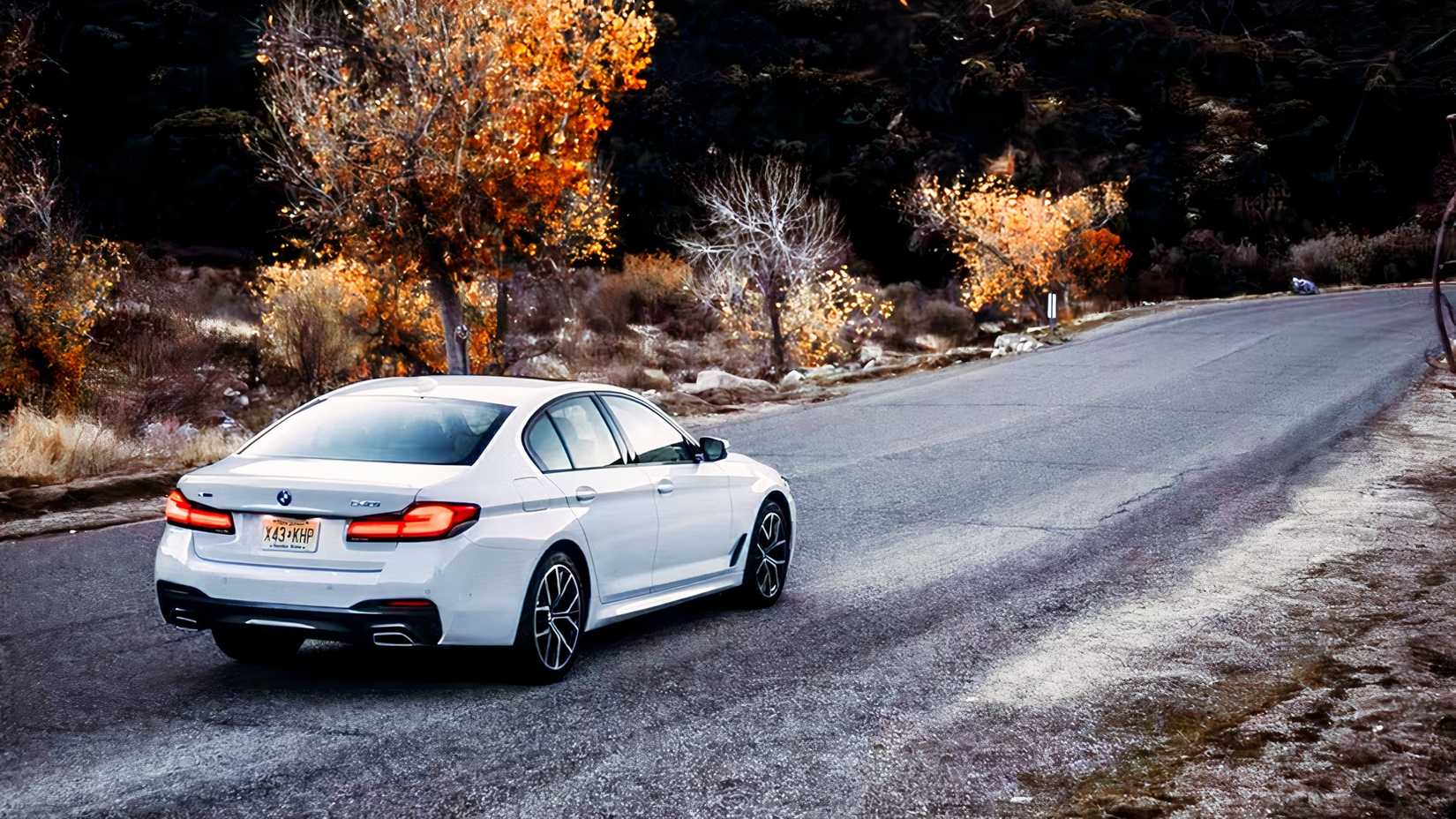 Rear 3/4 action shot of 2021 BMW 5 Series sedan driving on road