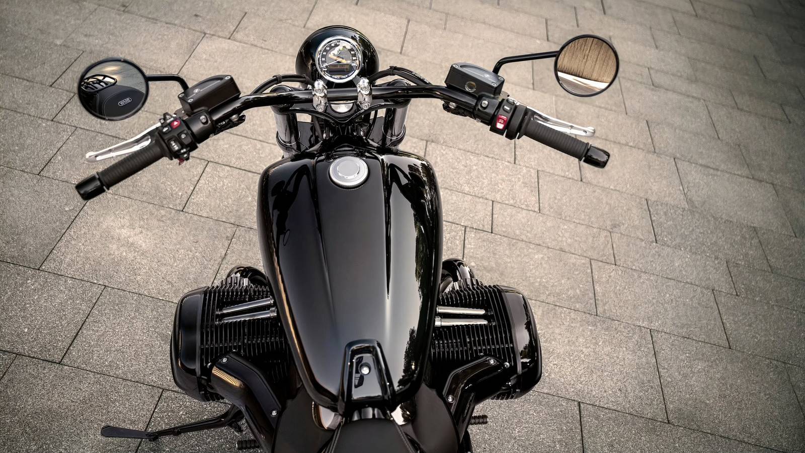 Una moto BMW R 18 con motore boxer e design retrò parcheggiata in un vialetto, con dettagli di ingegneria analogica visibili