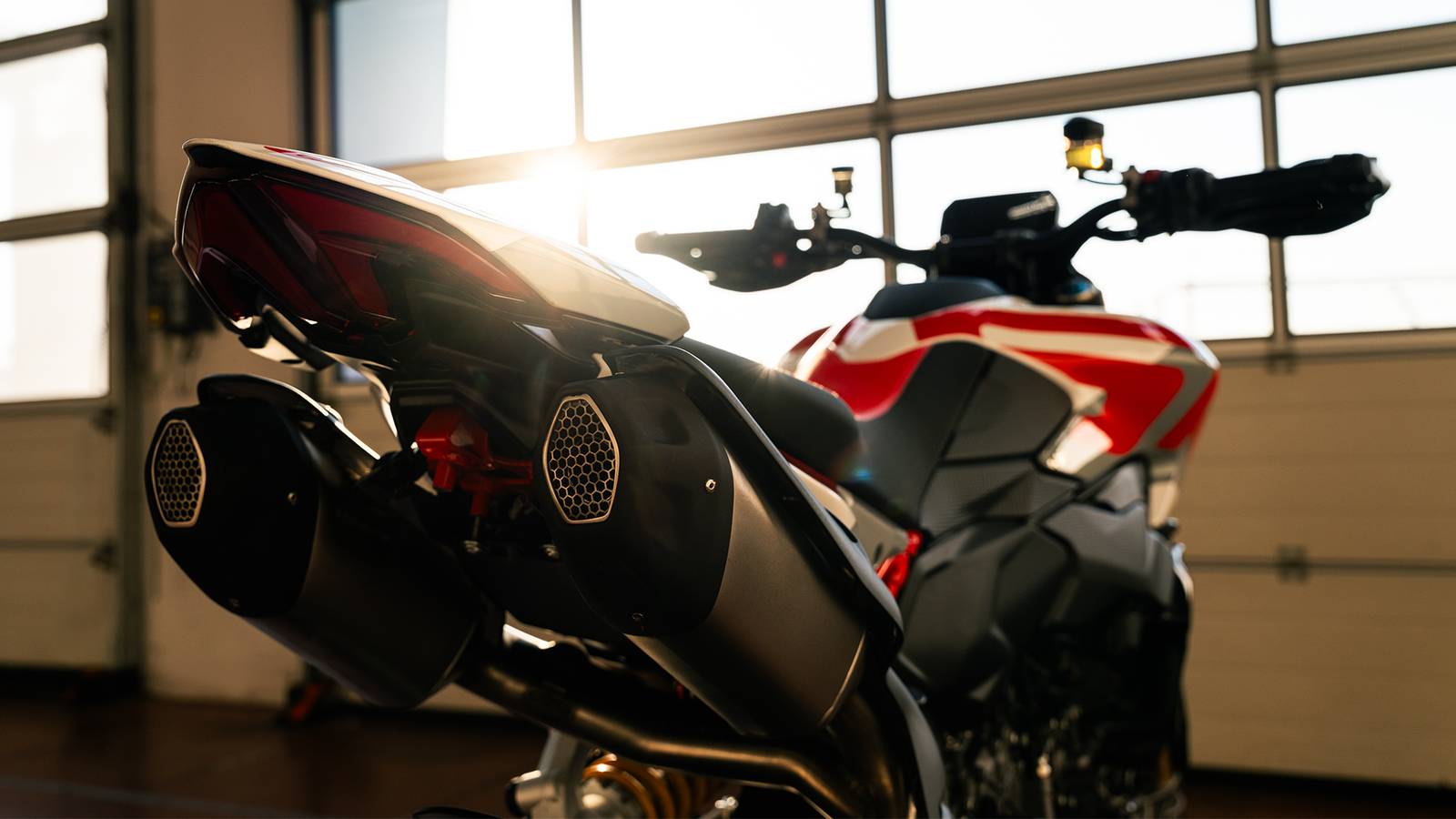 Moto con motore V-twin in azione su strada e pista, con dettagli di design e prestazioni