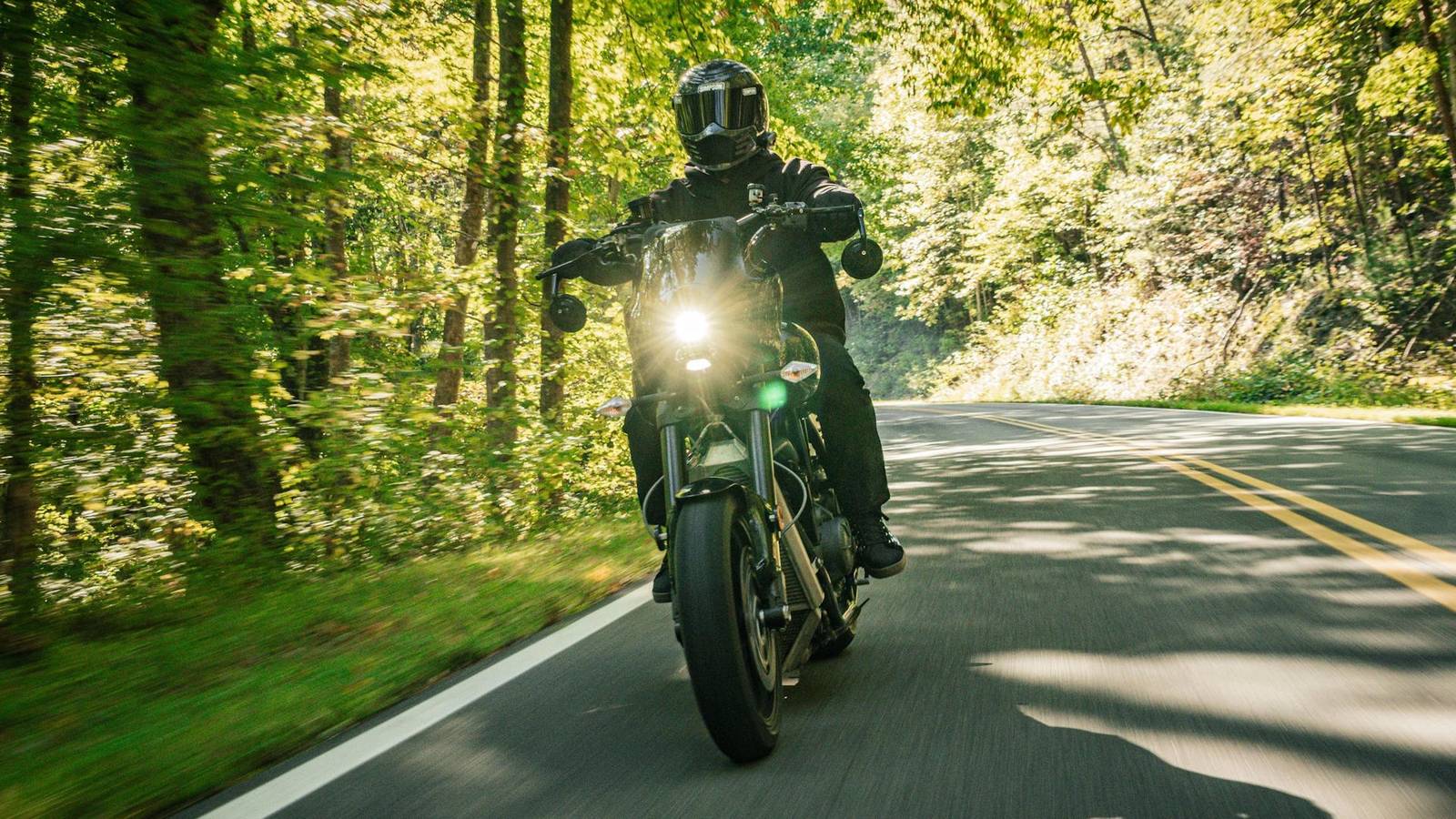Un rider su una motocicletta americana, con la strada e il paesaggio intorno