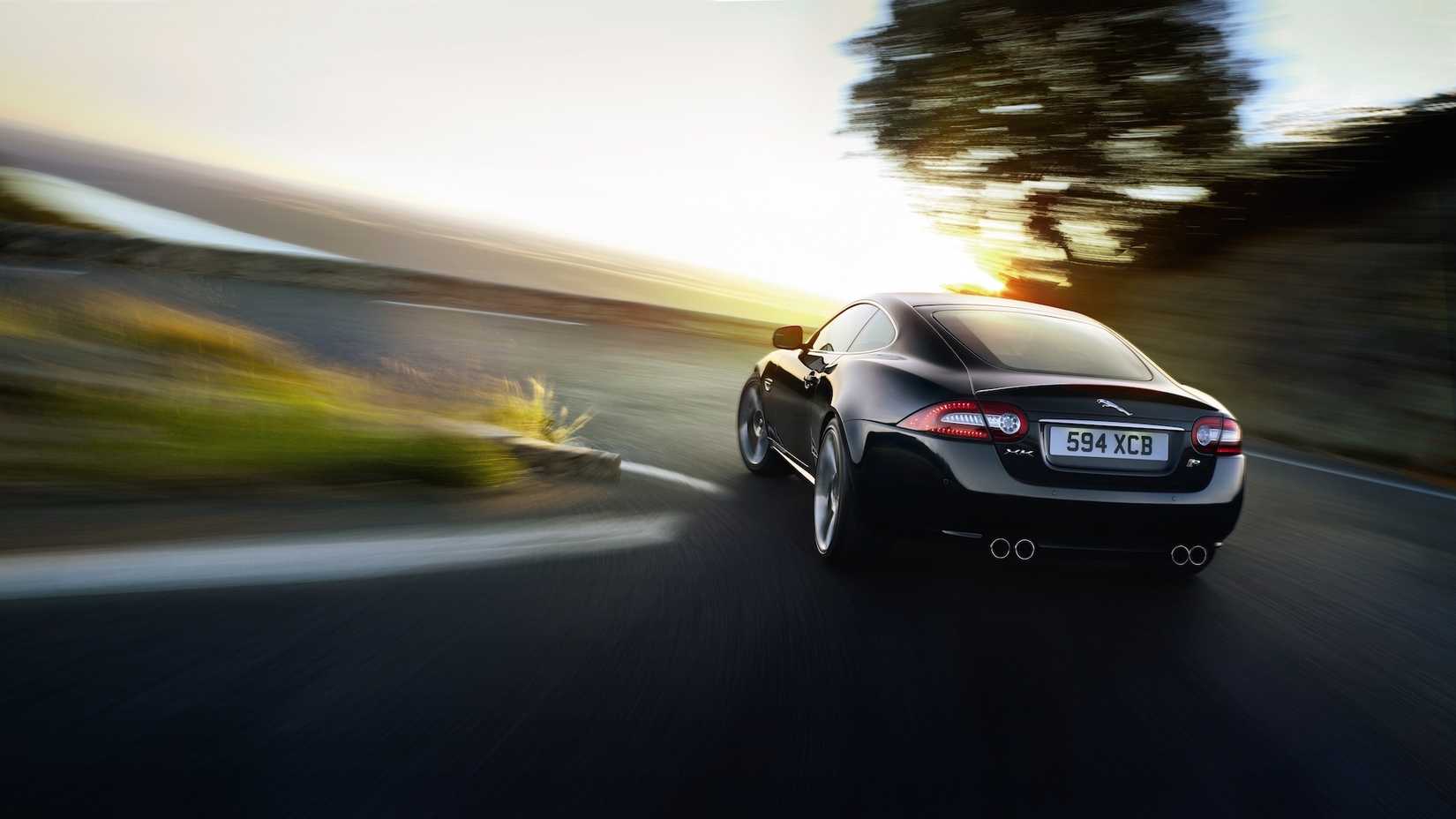 A 2011 Jaguar XKR drives around a corner with a blurred background
