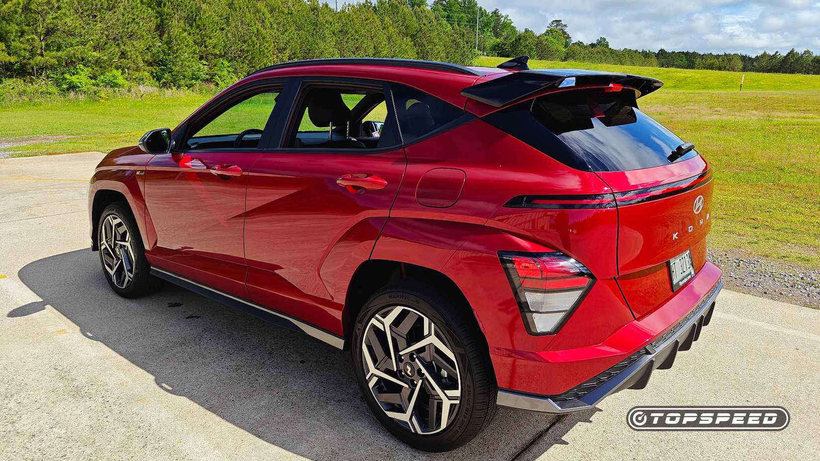 2024 Hyundai Kona N Line in red, parked on asphalt with a rear 3/4 view