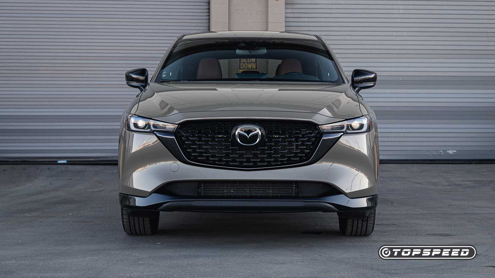Foto frontal do Mazda CX-5 Carbon 2024 estacionada em frente à garagem