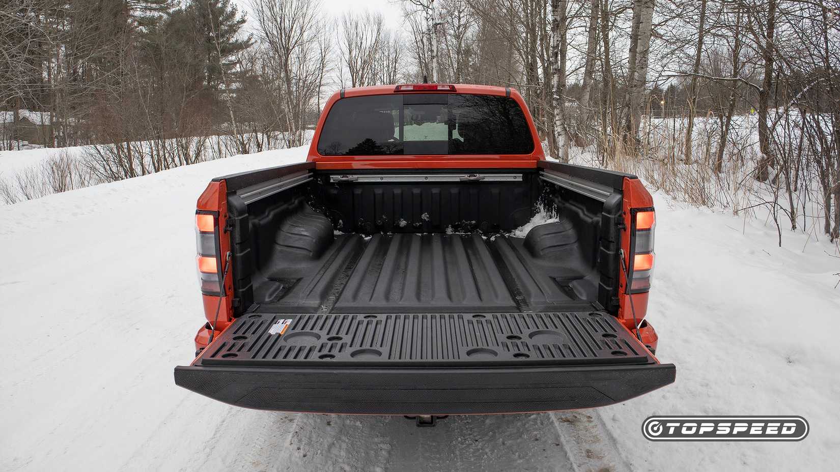Foto traseira da caçamba de um Nissan Frontier Pro-4X 2025 com a porta traseira abaixada