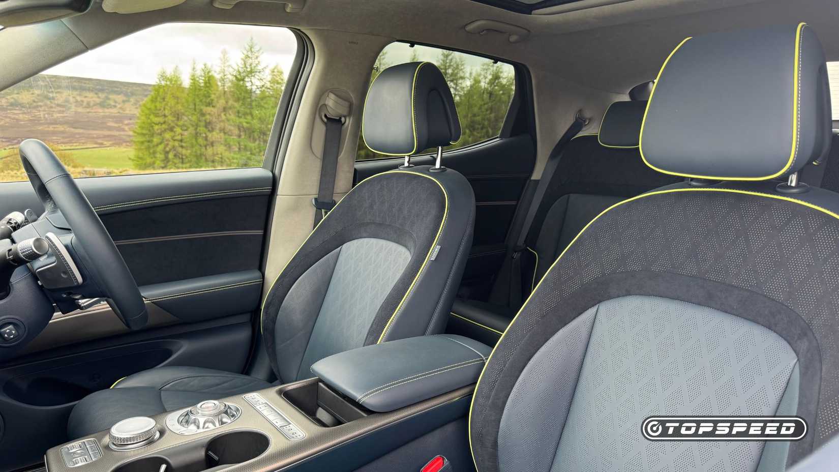 Shot of the front seats in the 2024 Genesis GV60 Sport Plus AWD with navy blue leather and lime green piping.