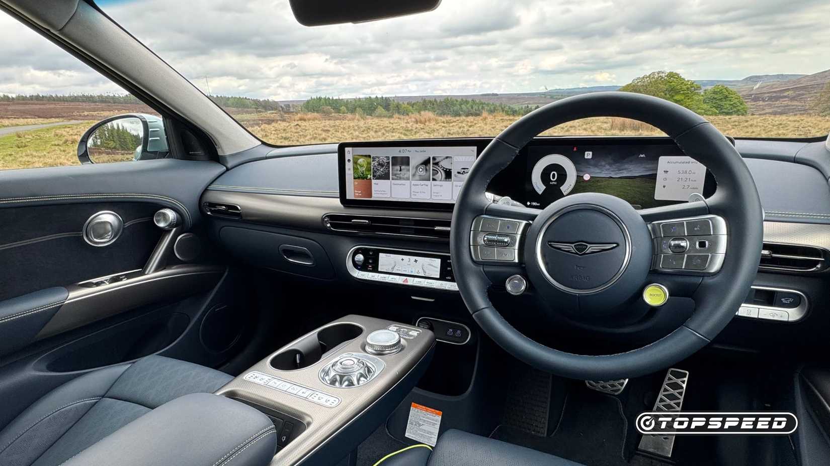 Close-up shot of the steering wheel and infotainment screen in a 2024 Genesis GV60 Sport Plus AWD.