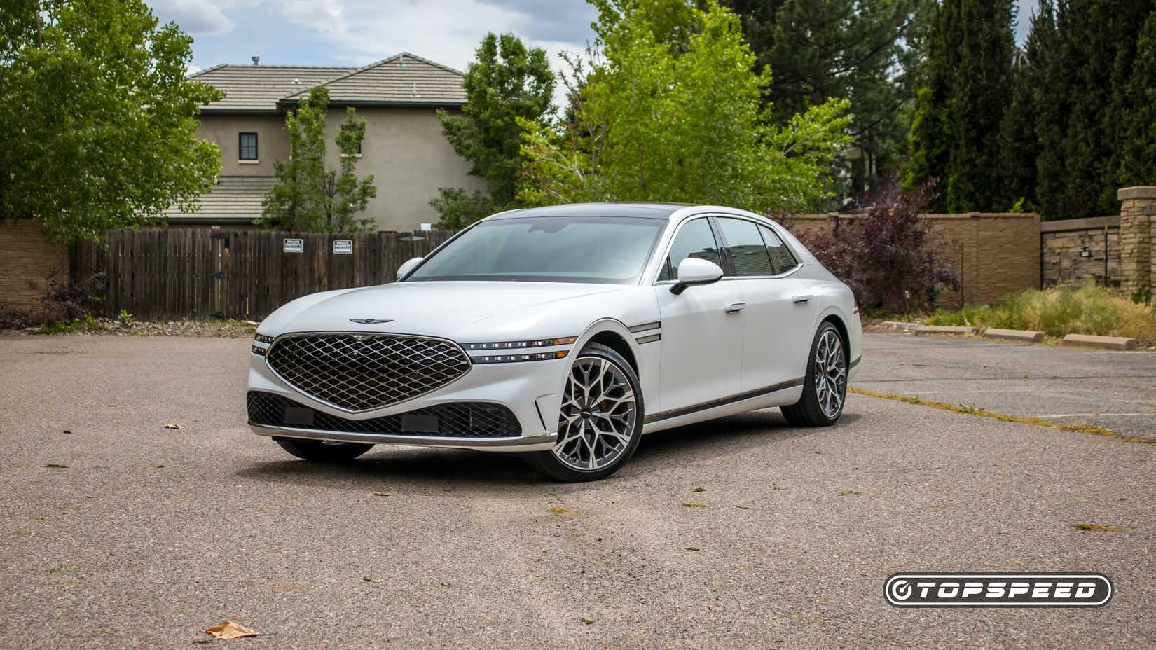 Front 3/4 shot of a 2025 Genesis G90 parked in front of house