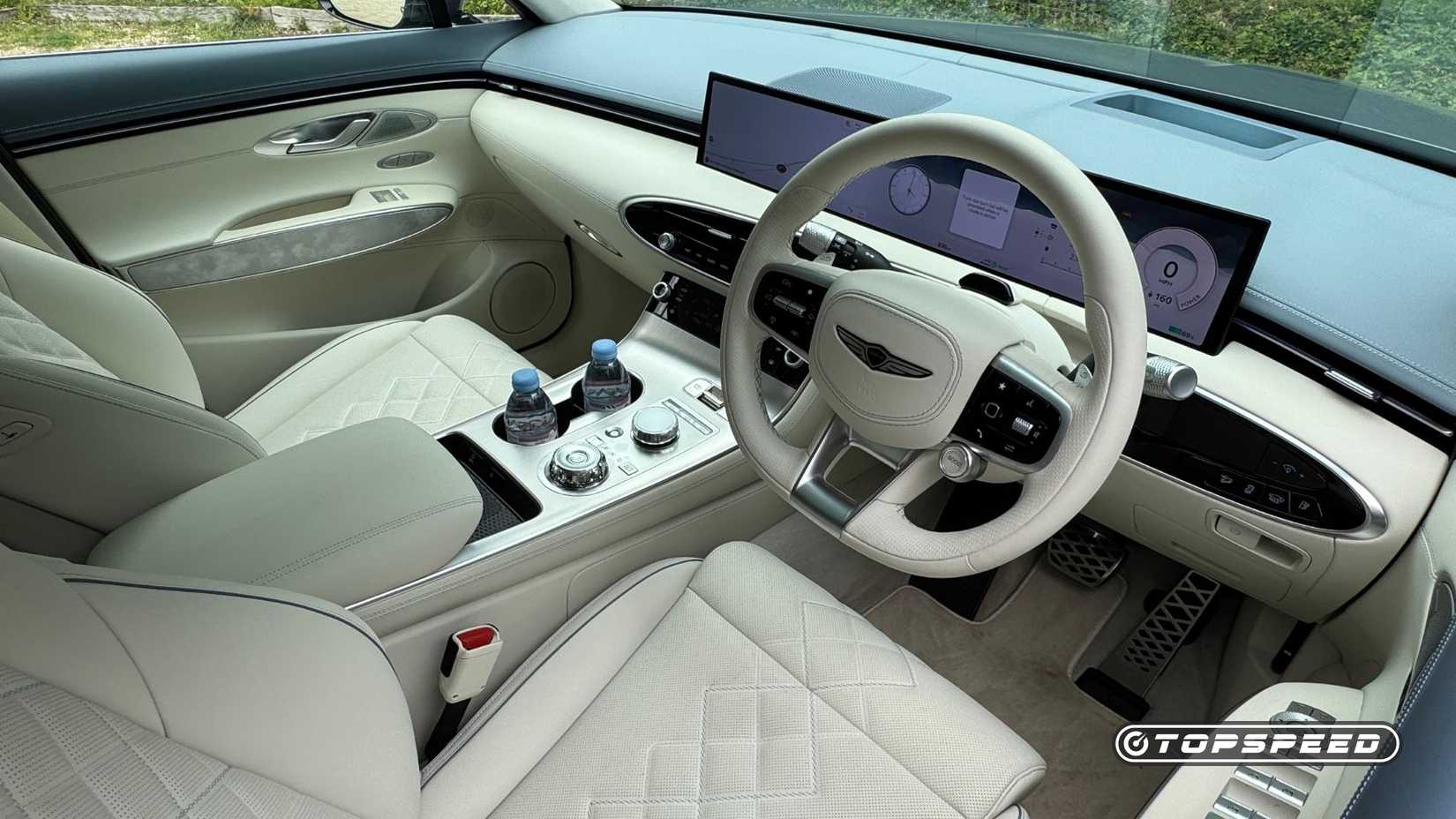 Close-up shot of the front seats in a 2026 Genesis Electrified GV70, including the steering wheel and infotainment screen.