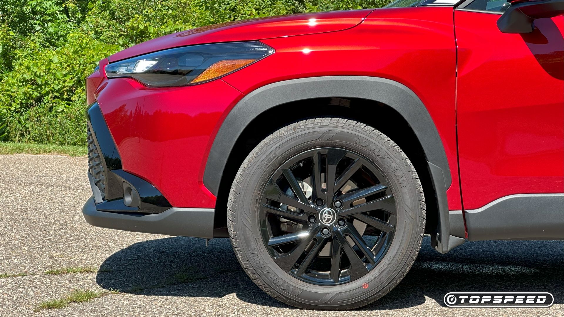 Front-end close-up of a red 2025 Toyota Corolla Cross Hybrid Nightshade's wheel