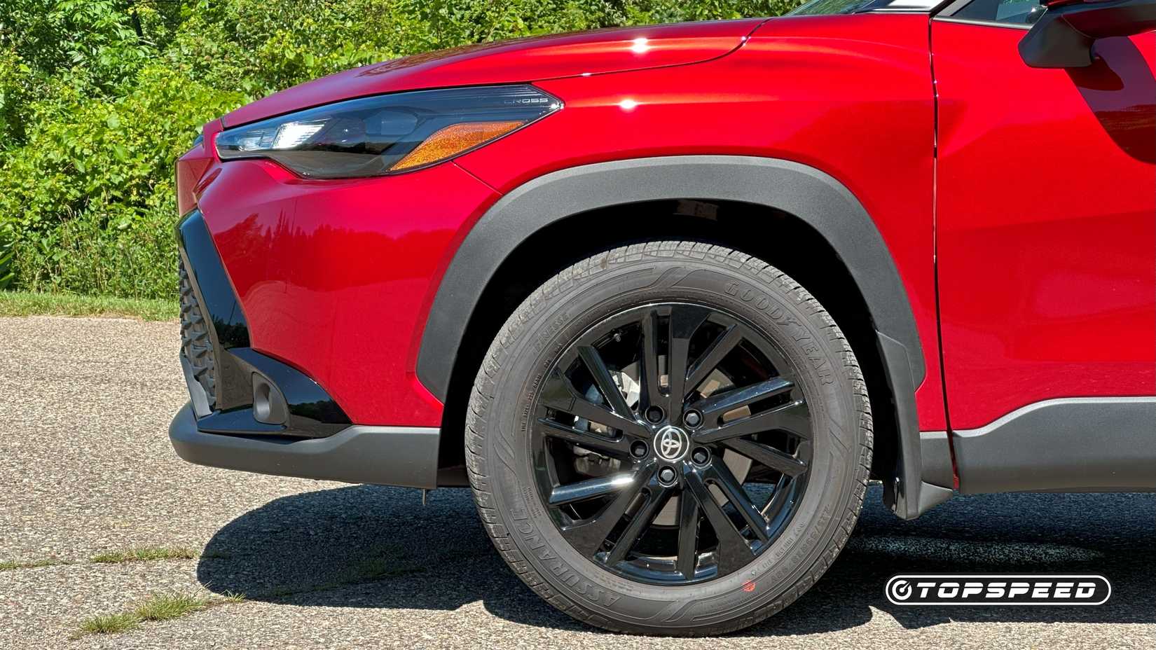 Front-end close-up of a red 2025 Toyota Corolla Cross Hybrid Nightshade's wheel