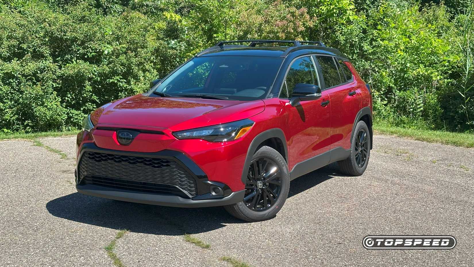 Front 3/4 shot of a red 2025 Toyota Corolla Cross Hybrid Nightshade parked in empty lot