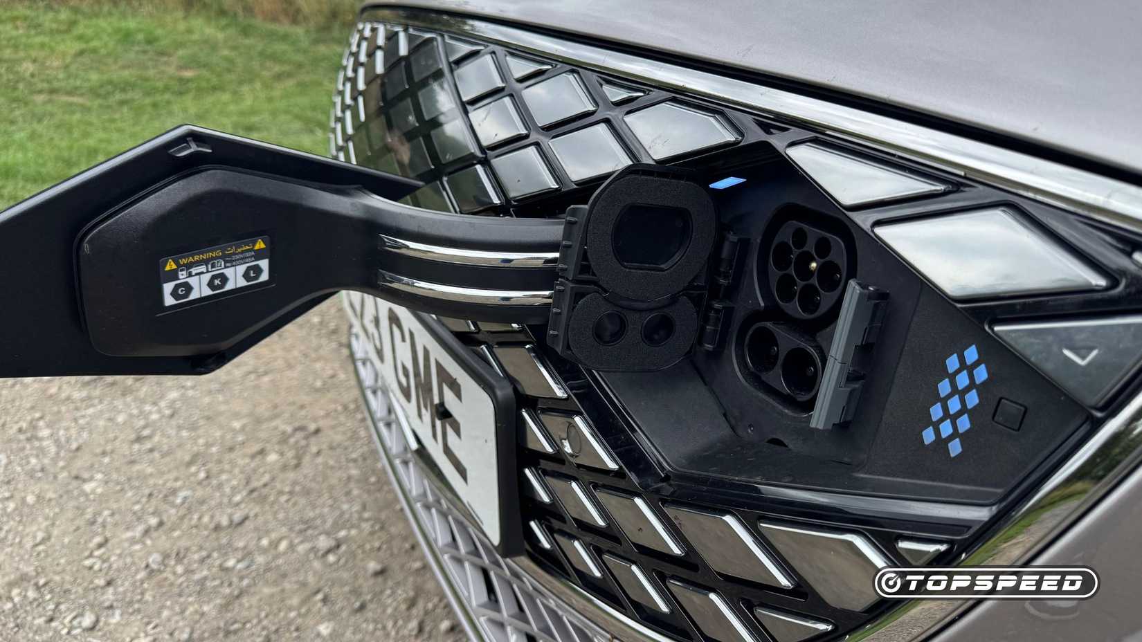 Close-up shot of the charging port built into the grille of a silver 2026 Genesis Electrified G80.