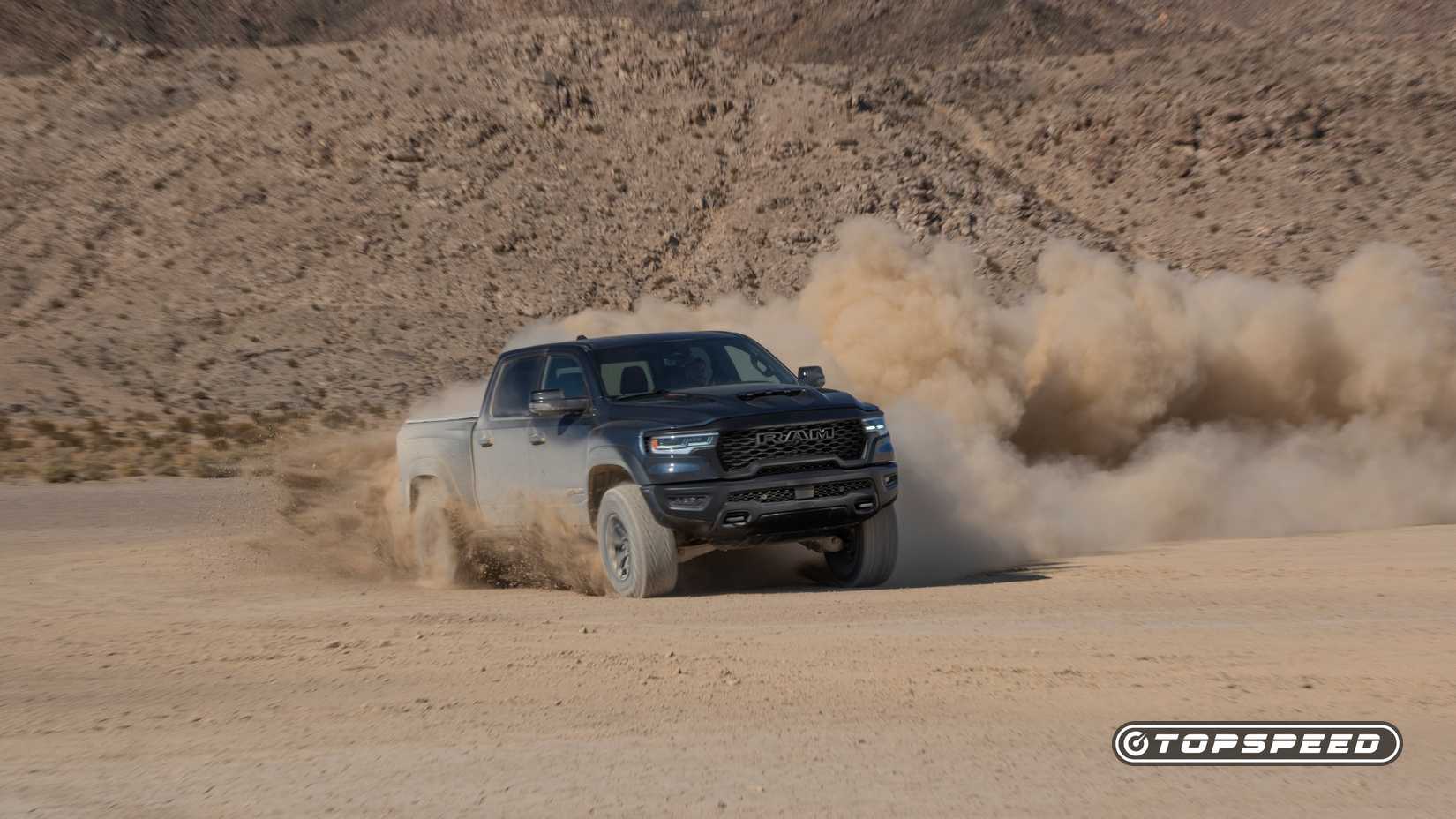 A 2025 blue Ram 1500 RHO off-roading in a desert