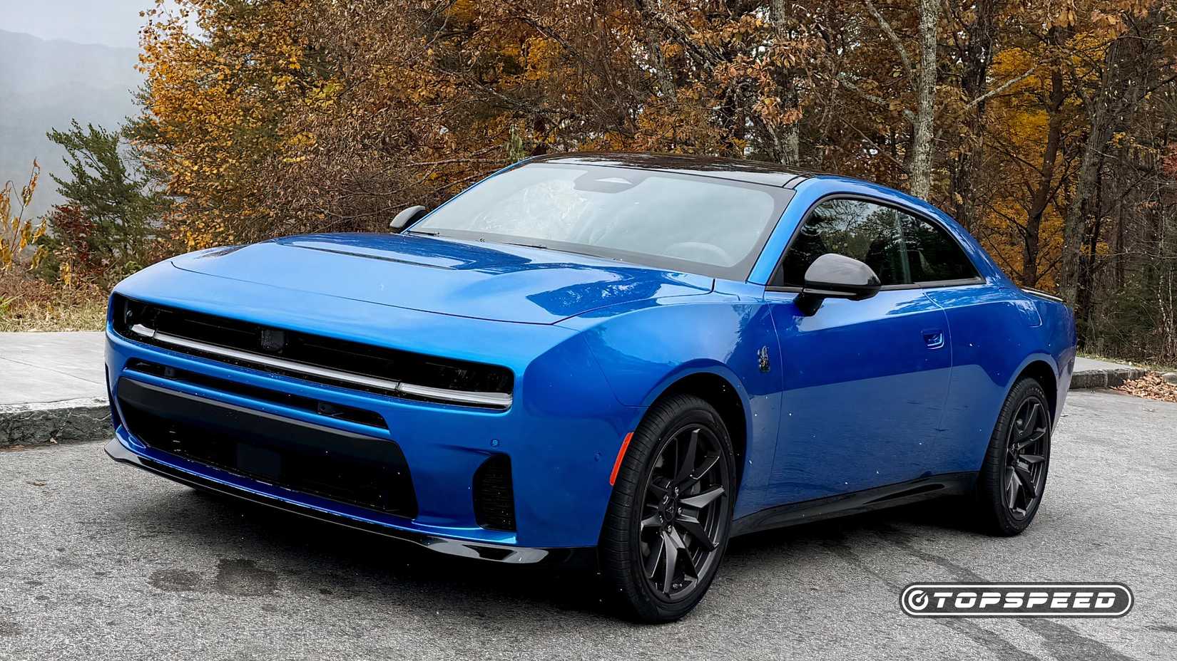 Foto frontal 3/4 de um Dodge Charger 2026 azul estacionado na beira da estrada