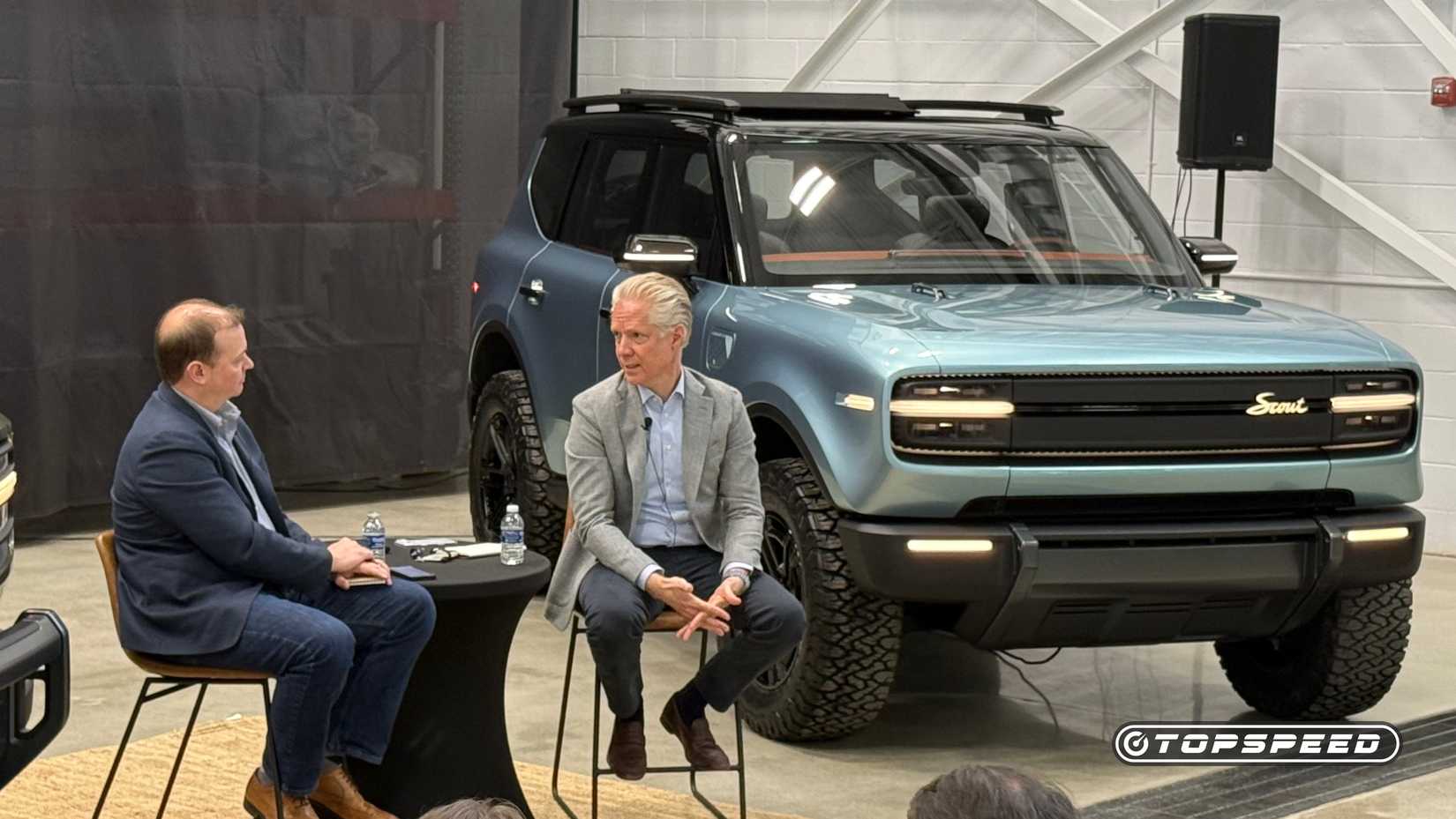 Scout Motors President And CEO Scott Keogh seated in front of Scout Traveler SUV at a press event