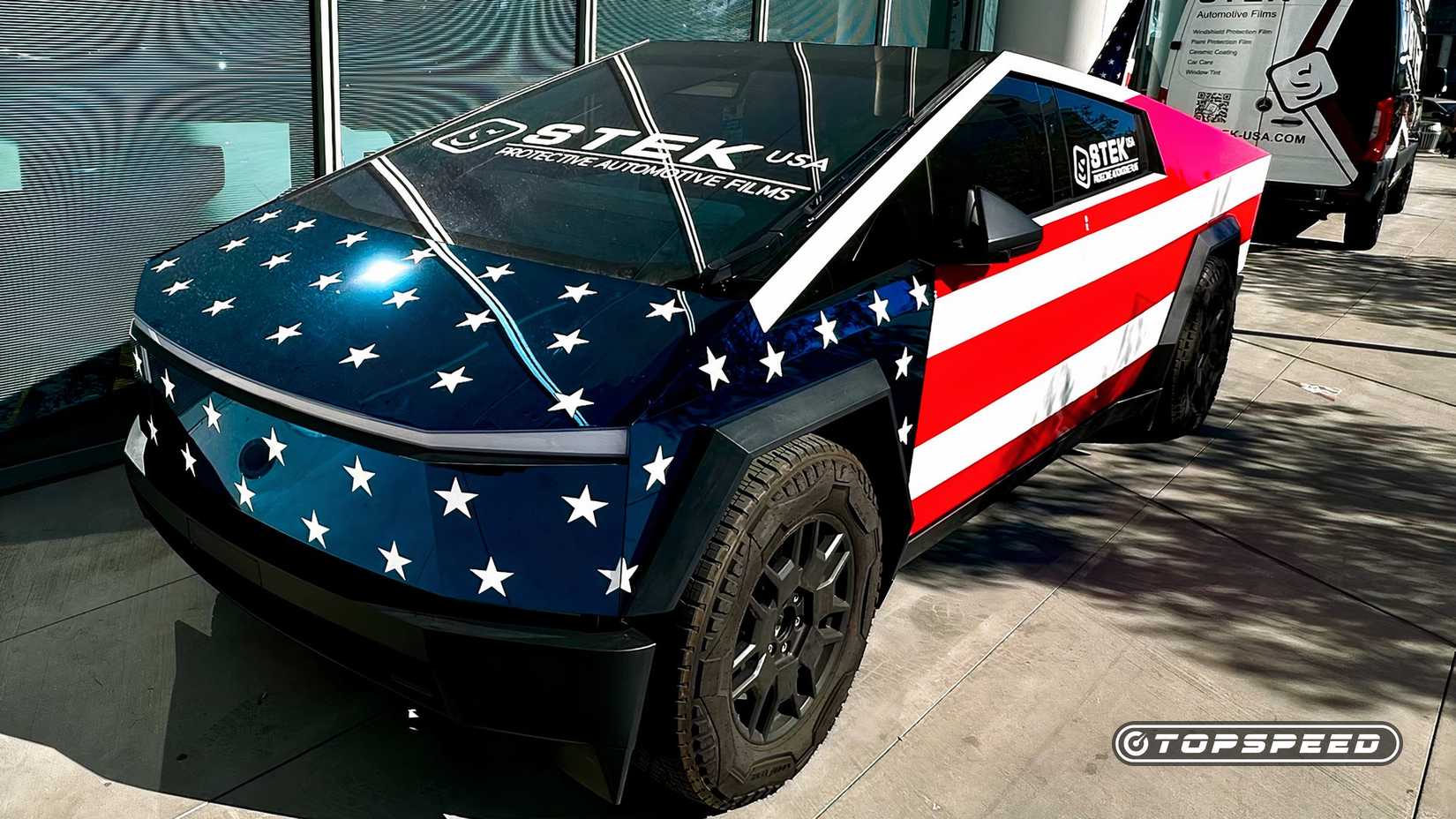 Vista lateral do motorista de um Tesla Cybertruck com envoltório personalizado estilo bandeira americana