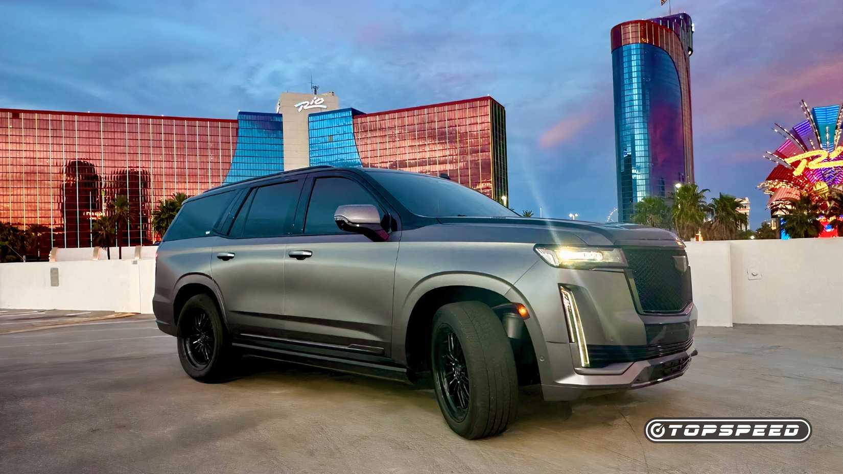 Cadillac Escalade 2024 com envoltório personalizado mostrado na frente e no ângulo lateral do passageiro no artigo sobre preços ocultos da concessionária.